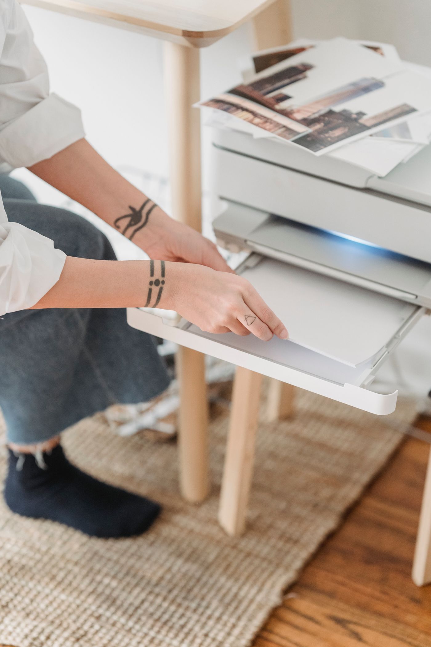 Hands loading paper into a home printer.