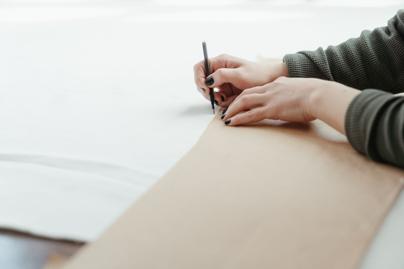 Hands drafting a pattern on paper.