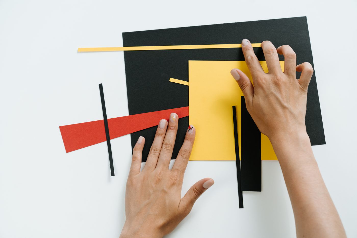 Hands arranging coloured paper to explore a graphic layout.