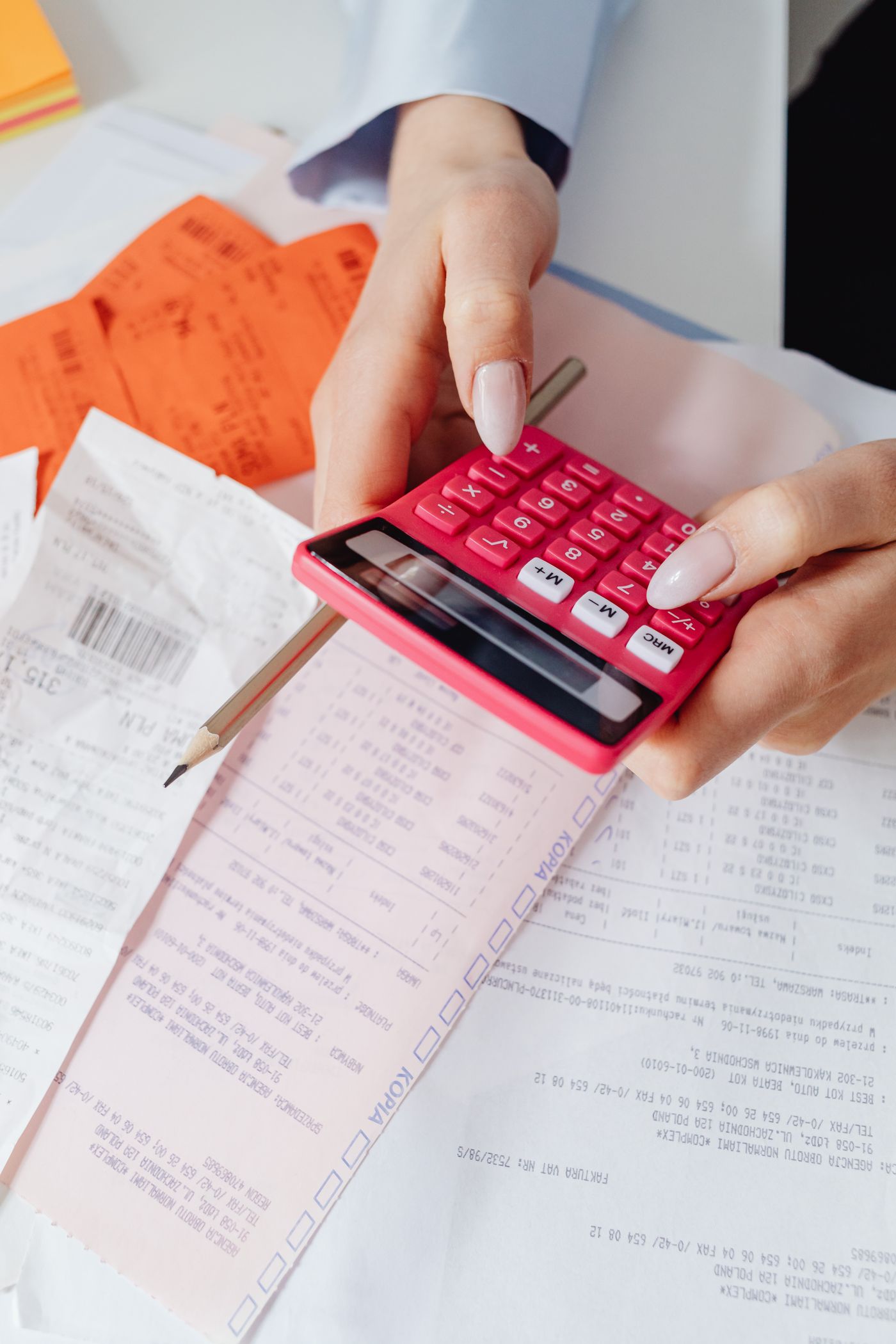 Hands using a calculator alongside receipts.