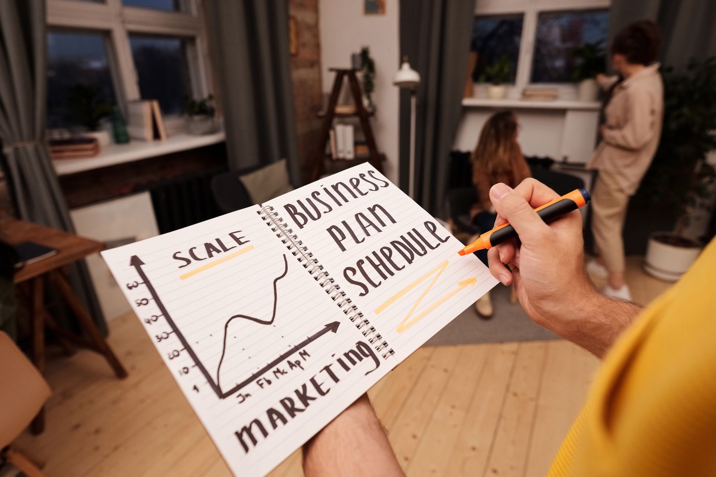 A person writing notes in a business planning notebook.