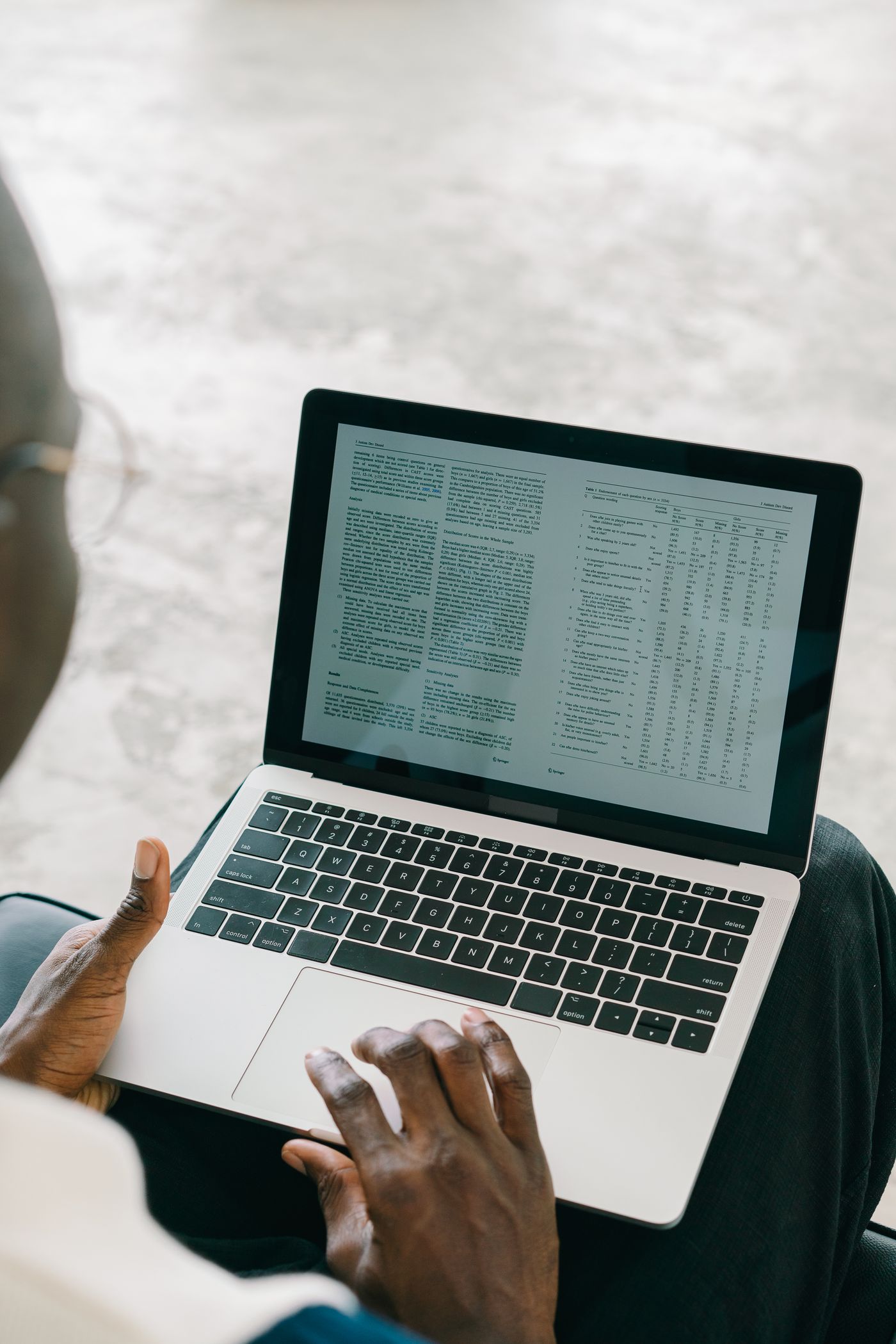 A person inspecting a document and table on a laptop.